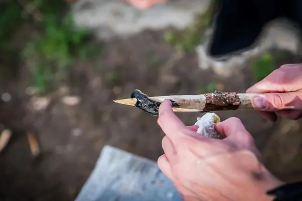 Holzstück wird mit einer Klinge bearbeitet, um eine Spitze zu formen