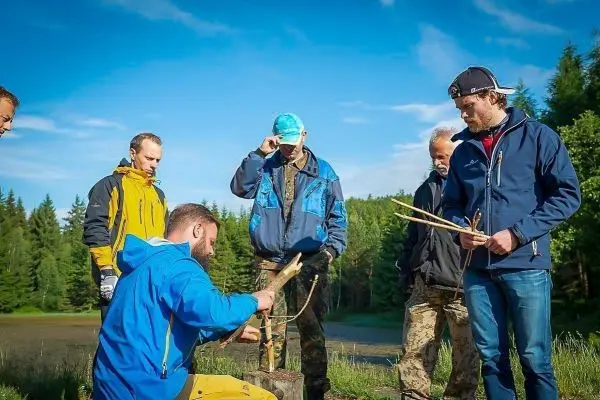 Mann bearbeitet Holzstück mit zwei Stöcken in der Natur