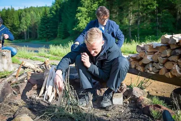 Mann bereitet Zunder in einem Feuerkreis aus Steinen vor