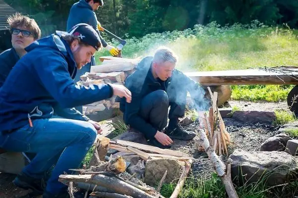 Mann entzündet Zunder in einem kleinen Bodenfeuer mit Rauchentwicklung