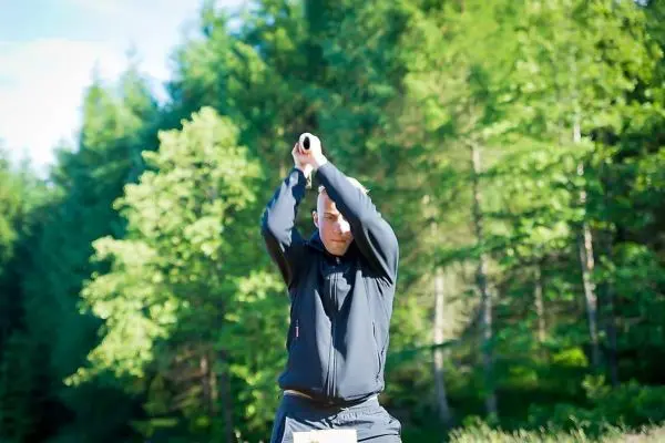 Mann hebt einen Stock über den Kopf in einem Waldgebiet