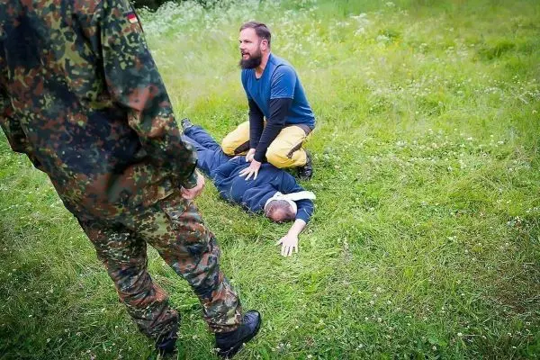 Mann leistet Erste Hilfe bei bewusstlosem Liegen auf Grasfläche
