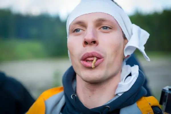 Mann mit einem Insekt im Mund und einem Kopfverband