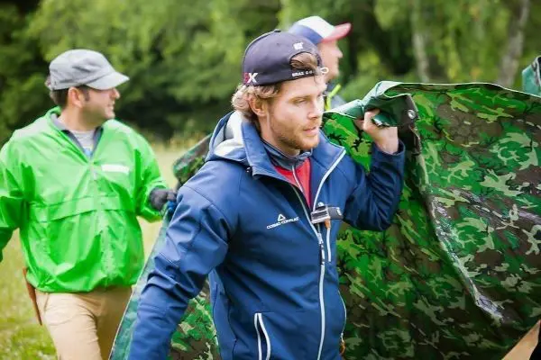 Mann trägt eine grüne, camouflierte Plane über die Schulter