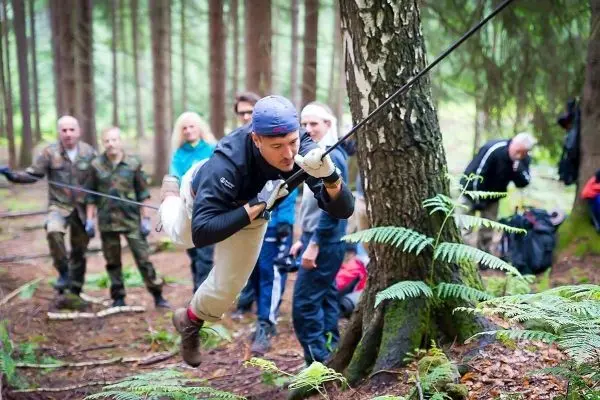 Mann überquert selbstgebaute Seilbrücke zwischen Bäumen im Wald