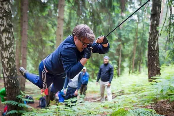 Mann überquert selbstgebaute Seilbrücke zwischen Bäumen im Wald