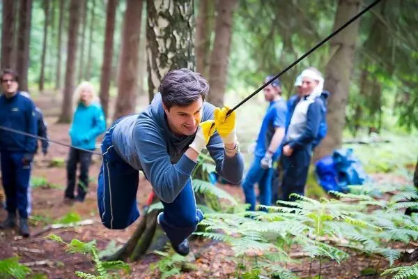 Mann überquert selbstgebaute Seilbrücke zwischen Bäumen im Wald