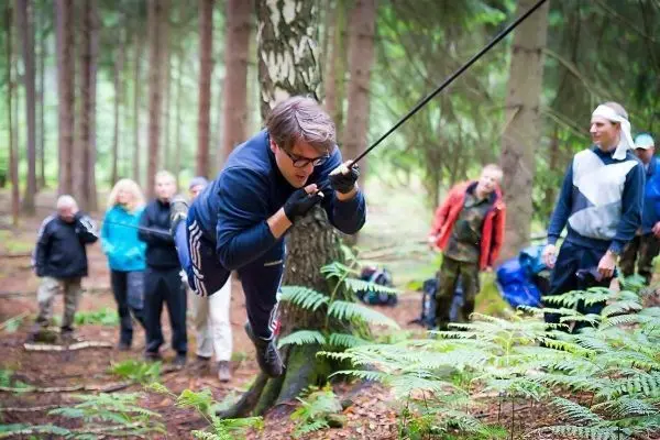 Mann überquert selbstgebaute Seilbrücke zwischen Bäumen im Wald