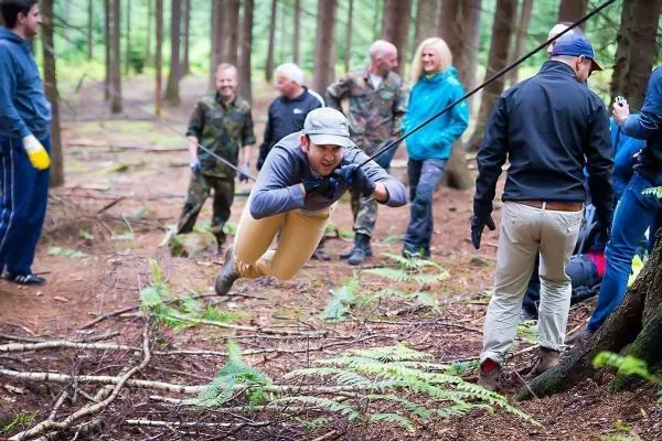 Mann überquert selbstgebaute Seilbrücke zwischen Bäumen im Wald