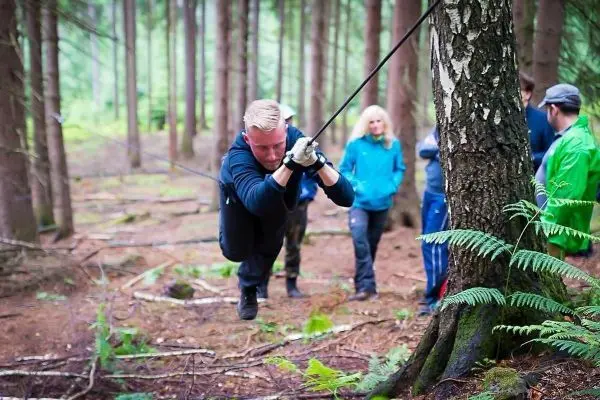 Mann zieht an einem Seil, während andere Personen im Hintergrund beobachten