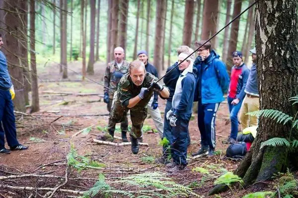 Mann zieht an einem Seil, während andere zuschauen und helfen