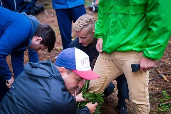 Mehrere Personen binden Pflanzenmaterial um ein Bein zur Stabilisierung