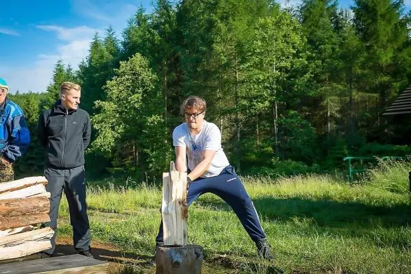 Messer schlägt auf Holzscheit, während Zuschauer beobachten