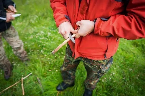 Messer schneidet Holzstück in der Hand eines Teilnehmers