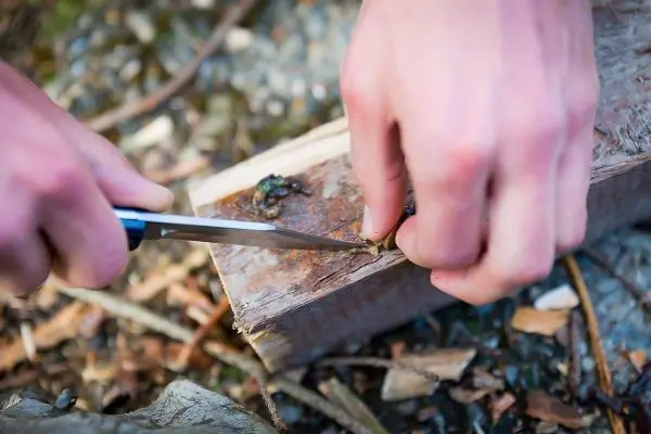 Messer schneidet in ein Stück Holz auf dem Boden