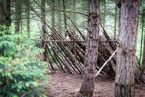 Person baut eine selbstgebaute Seilbrücke im Wald