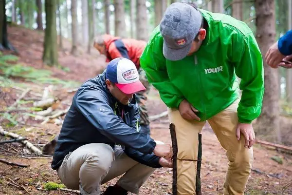 Person befestigt einen Stock im Wald