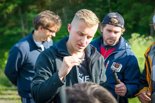 Person hält einen Gegenstand in der Hand und spricht mit anderen