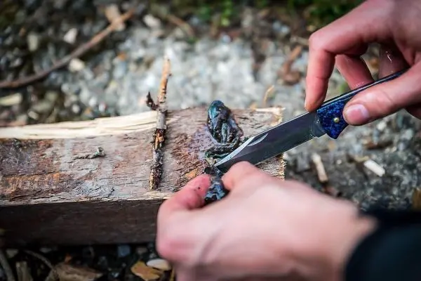 Person schnitzt mit einem Messer an einem Holzstück