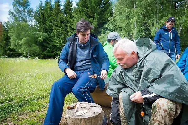 Person zeigt einer anderen Person eine Technik am Holzstück beim Überlebenstraining