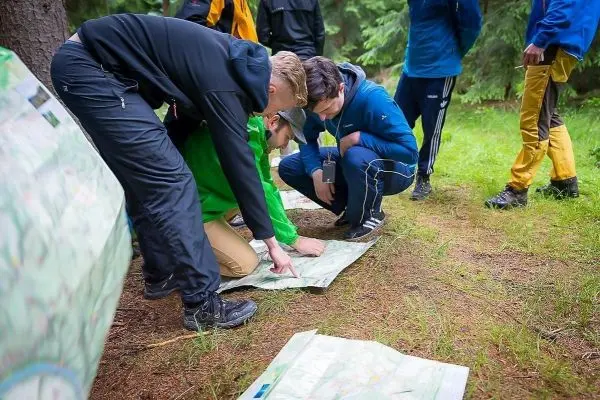 Personen betrachten Karten auf dem Boden im Wald