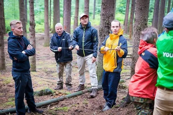 Seilquerung mit mehreren Personen im Wald, eine Person hält ein Seil
