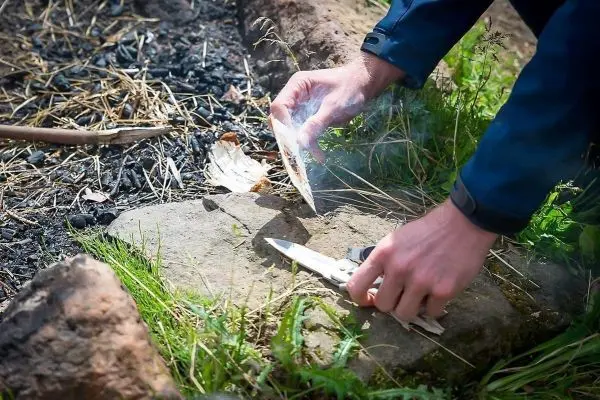 Zunder wird mit einem Messer bearbeitet, Rauch steigt auf