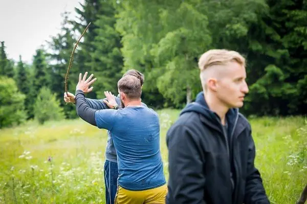 Zwei Personen im Freien, eine hält einen Stock in der Hand