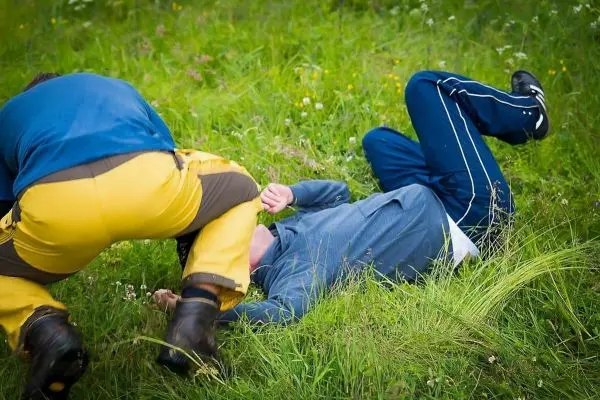 Zwei Personen liegen im Gras, eine Person greift die andere an