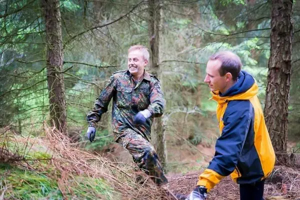 Zwei Personen sammeln Laub im Wald und tragen Handschuhe