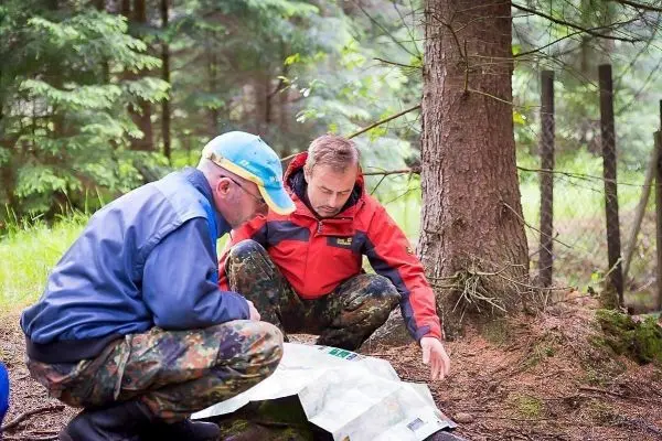 Zwei Personen studieren eine Karte im Wald, um sich zu orientieren