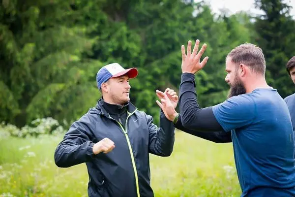 Zwei Personen üben eine Handtechnik im Freien auf einer Wiese