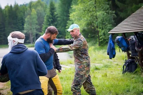 Zwei Personen üben eine Selbstverteidigungstechnik am Ufer eines Gewässers
