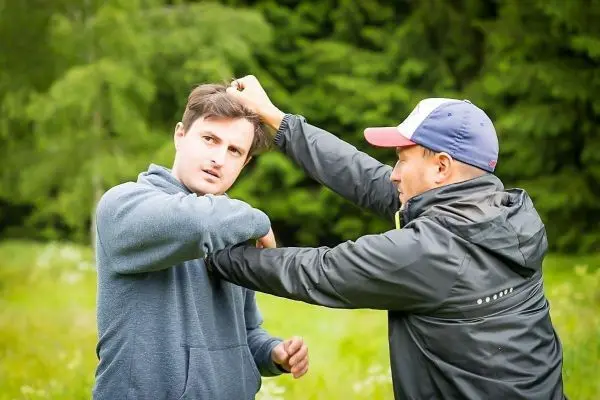 Zwei Personen üben eine Selbstverteidigungstechnik im Freien