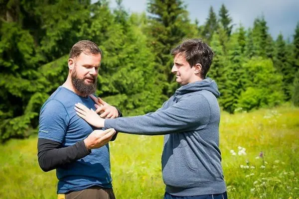Zwei Personen üben eine Technik zur Selbstverteidigung im Freien