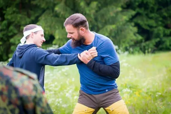 Zwei Personen üben einen Nahkampfgriff auf einer Wiese