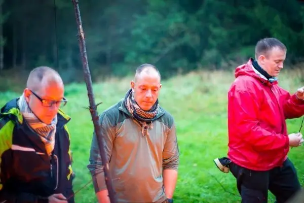 Drei Personen stehen in der Natur und arbeiten an einer Seilquerung