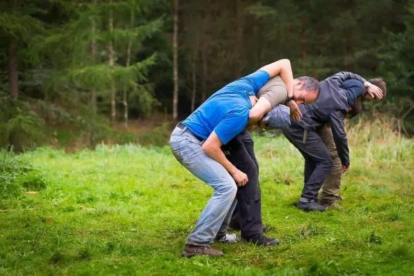 Drei Personen üben eine Technik zur Unterstützung oder Rettung im Gelände