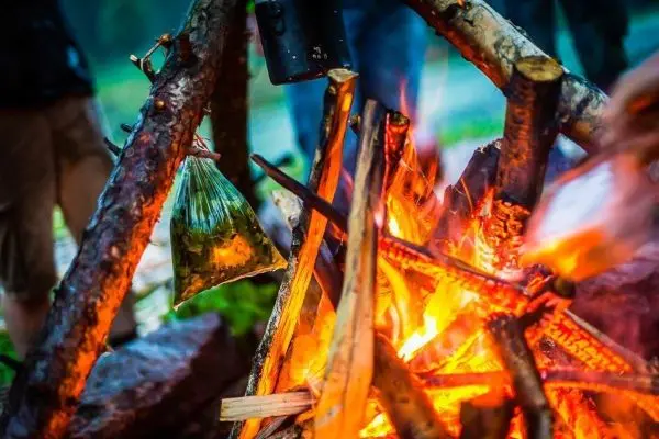 Ein Beutel hängt über einem Feuer aus Holzscheiten