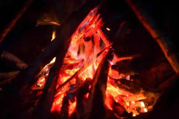 Feuer brennt zwischen Holzstücken im Dunkeln