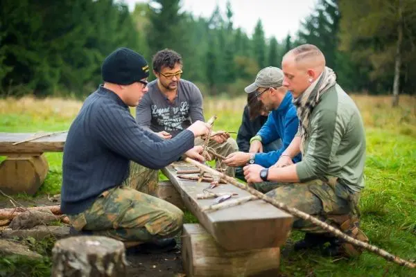 Fünf Personen arbeiten an einem Tisch mit Holzstücken und Werkzeugen