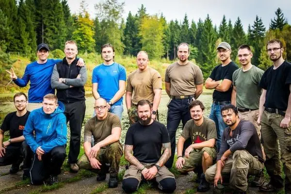 Gruppe von Männern posiert am Ufer eines Gewässers im Wald
