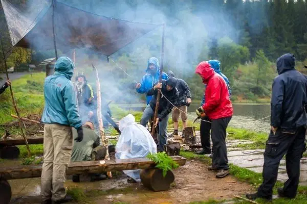 Gruppierung unter Tarp-Notunterkunft, Rauch steigt von kleinem Bodenfeuer auf