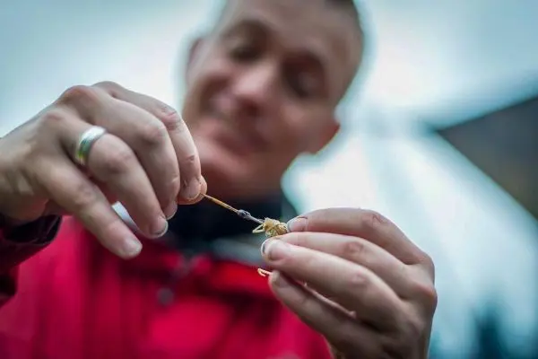 Hände halten einen kleinen Gegenstand mit einem dünnen Faden