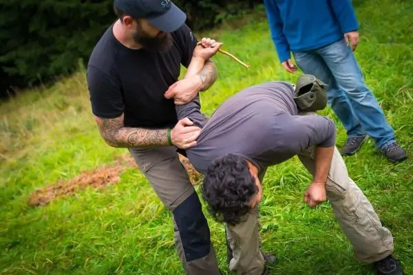 Kampftechniken werden demonstriert, während ein Teilnehmer einen anderen kontrolliert
