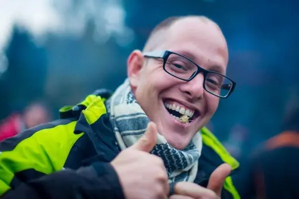 Lächelnder Mann mit Daumen hoch und einem Blatt im Mund