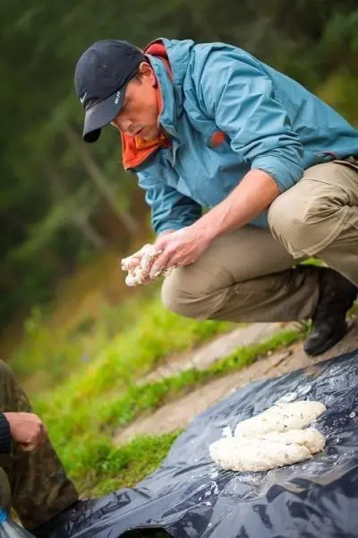 Mann knetet eine Mischung auf einer schwarzen Plane im Freien