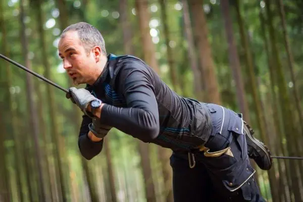 Mann überquert eine selbstgebaute Seilbrücke im Wald