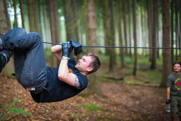 Mann überquert selbstgebaute Seilbrücke im Wald