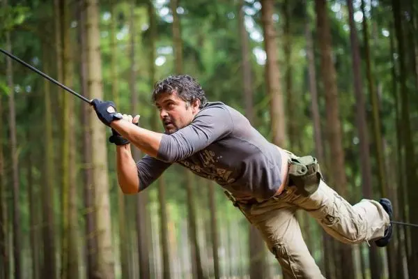 Mann überquert selbstgebaute Seilbrücke im Wald